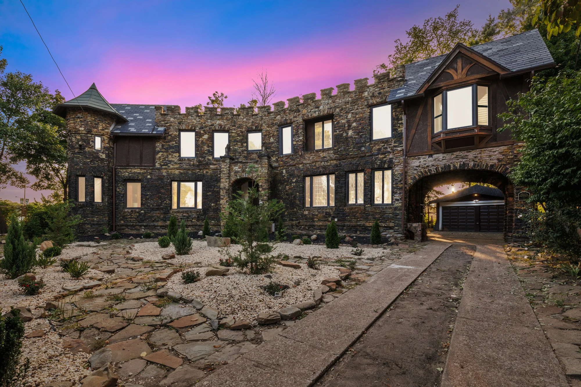 Distinctive stone castle property beneath a vivid pink and blue sunset sky