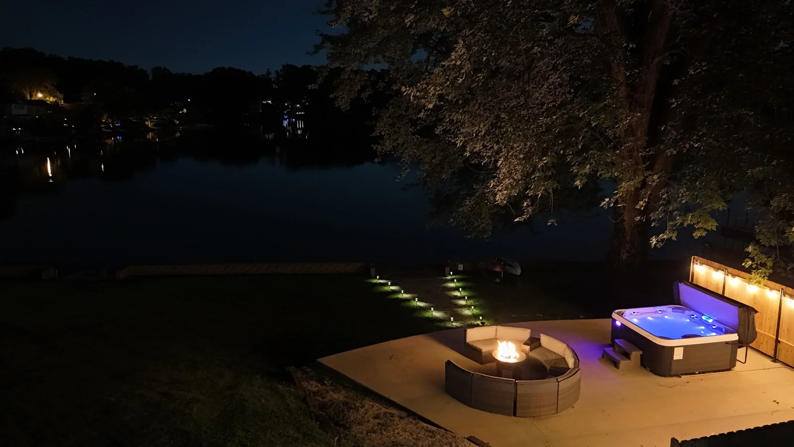 Lakefront short-term rental at night with hot tub and fire pit